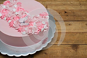 Pale pink cake decorated with meringue flowers and edible paper butterfly