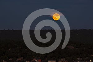 Pale Pink Clouds Crossing in Front of Orange Supermoon at Dusk