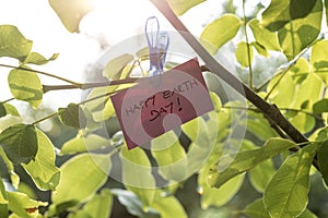 Pale pink coloured piece of paper holding a sign Happy Earth day