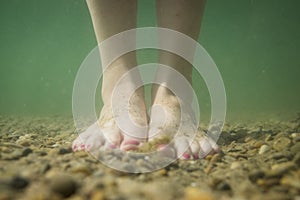 Feet underwater on stoney and muddy ground