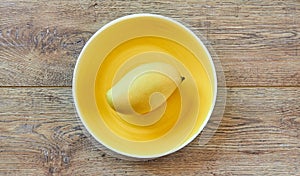 Pale yellow mango on a bright yellow plate on a wooden tabletop