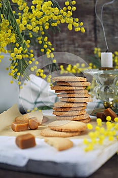 Palets bretons, french cookies. Salted caramel Shortbread Breton cookies and bouquet of mimosa photo