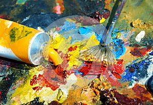 Palette of the artist with tubes of paint and brushes.