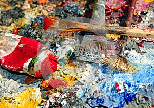 Palette of the artist with tubes of paint and brushes.