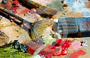 Palette of the artist with tubes of paint and brushes.