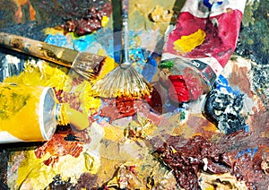 Palette of the artist with tubes of paint and brushes.