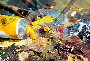 Palette of the artist with tubes of paint and brushes.