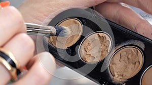 Palette with beige eyeshadows of different shades in the hands of a professional makeup artist