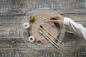 Palette with brushes and balls of cotton threads on the wooden table