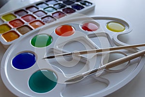 Palette with diluted multicolored paints and two brushes photo
