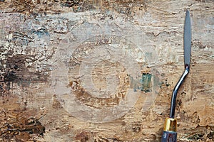 Palette knife on artist canvas with coating of brown oil paint