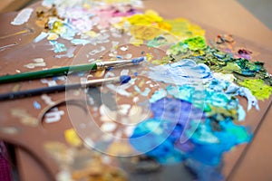 Palette with multi-colored paints and brushes, woman painting picture