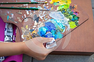 Palette with multi-colored paints and brushes, woman painting picture