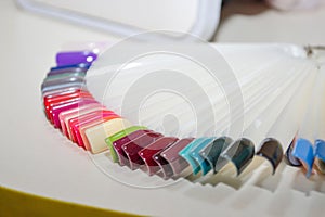 Palette of nail design of different colors with gel polish on white tips and background. Plastic testers for nail polish