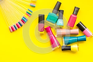 Palette and nail polish for nail artist work on yellow desk background top view
