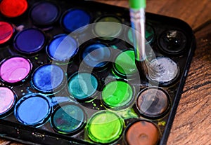 palette of watercolor paints and brushes on a wooden surface.top view.