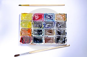 Palette with watercolors and brushes for paints on a white background