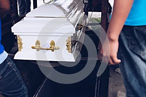 Pallbearers carefully oversee the process of lowering the casket to the ground for the deceased to its final place of rest