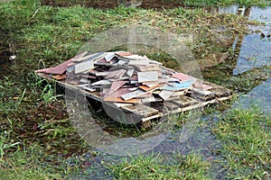 Pallet with broken tiles left on grass during flood