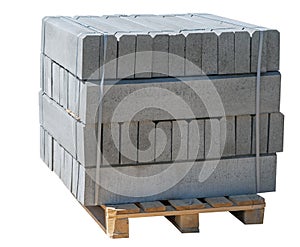 The pallet with a stack of concrete curbstone on white