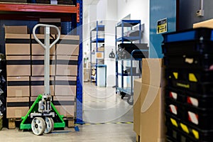 A pallet stacked with boxes ready to be shipped out. A pallet truck is sitting under the pallet to ready move it. Warehouse,