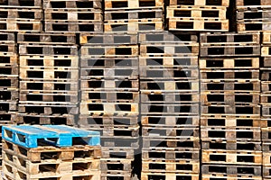 Pallets background. Stacks of old rough wooden pallets at warehouse in industrial yard. Cargo and shipping concept