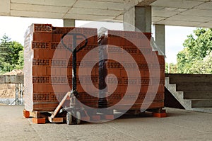Pallets with red bricks at the stage of construction in a new building