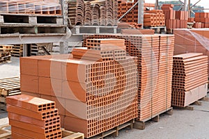 Pallets with stack of redbricks lying at warehouse
