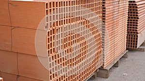 Pallets with stack of redbricks lying at warehouse of building materials in sunny day