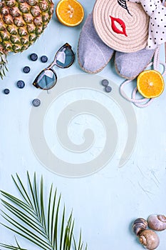 Palm branch, fruit, shoes and sunglasses, on a blue background, summer vacation. Free space for text. Copy space. Flat lay