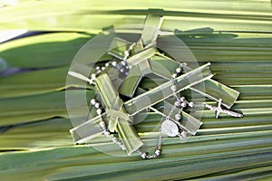 Palm crosses and rosary beads on palm leaves