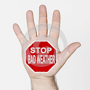 On the palm of the hand there is a stop sign with the inscription - STOP BAD WEATHER