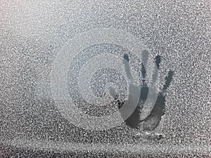 Palm print on the frozen glass. Trace hands and fingers on the window covered with snow frost