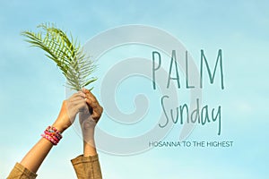 Palm Sunday quote - Hosanna to the highest. Fern or palm leaf in hands on bright and clear blue sky background. photo