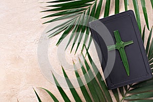 Palm Sunday concept. Palm cross on open Holy Bible and palm leaves. Reminder of Jesus sacrifice and Christ resurrection