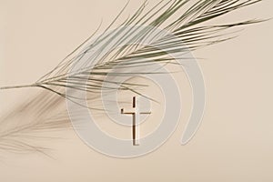 Palm Sunday and Easter concept. Cross or crucifix and palm leaf on light beige background