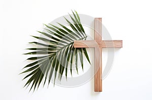 Palm Sunday. Wooden cross and palm leaf on white background with copy space.