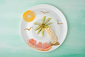 A palm tree and a sun of fruit, a creative of food on a white plate. Food Concept