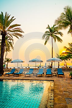 palm tree with umbrella chair pool in luxury hotel resort at sunrise times
