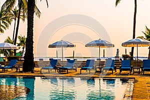 Palm tree with umbrella chair pool in luxury hotel resort at sunrise times