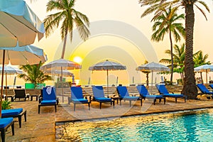 Palm tree with umbrella chair pool in luxury hotel resort at sunrise times