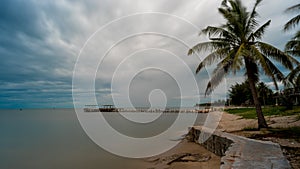 Palm tree and  walkeway in front of Dilapidated old fishing dock collapsing into the sea in Pak Nam Pran Thailand photo