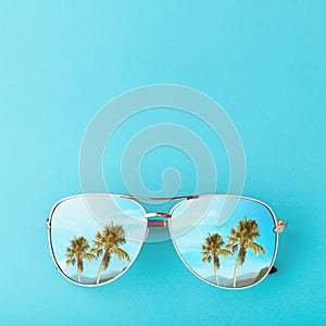 Palm trees and mountains are reflected in sunglasses. Concept on the theme of vacation and travel with copy space