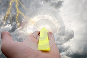 On  palm of your hand is a green arrow pointing to a stormy sky. The concept of business is in trouble