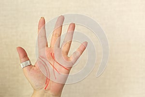 Palmistry. Female palm with life lines drawn with felt-tip pen isolated on light beige background