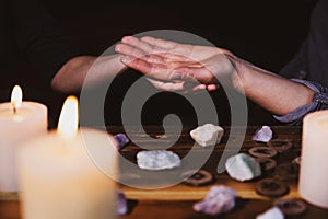 Palmistry or palm reading, fortuneteller holding a hand, healing stones and candles