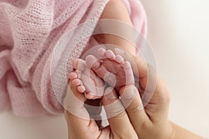 The palms of the father, the mother are holding the foot of the newborn baby