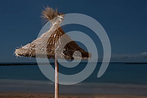 Palms parasol on empty beach on night time