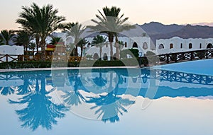 Palms reflection in pool at tropical sunset