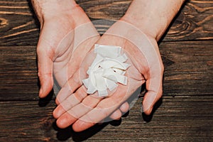 Palms with snus with nicotine pouches on a wooden background.